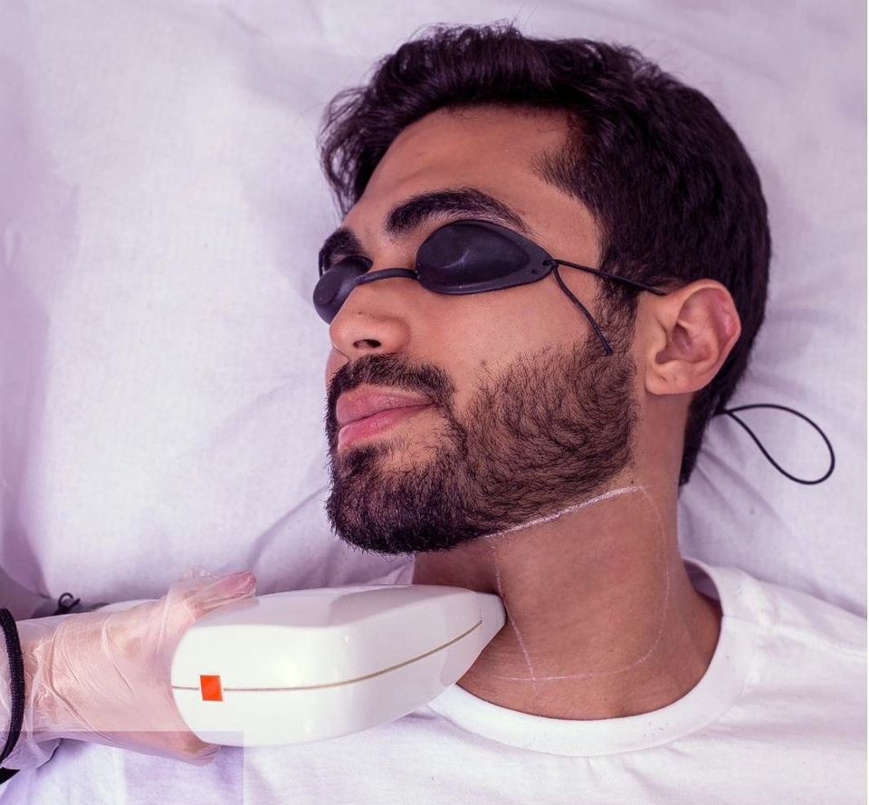 Cliente de óculos de proteção recebendo depilação a laser no pescoço