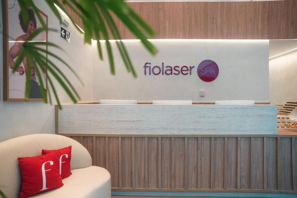 Recepção da Fiolaser SPA com o logo na parede e almofadas vermelhas